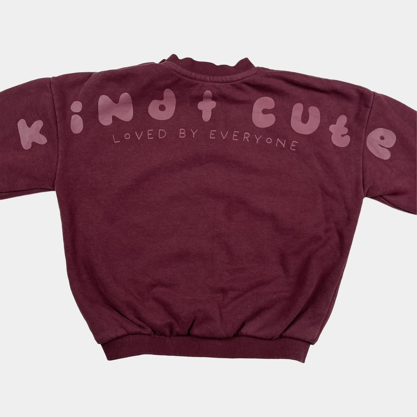 Bordeauxfarbener Pullover mit "Kind Cute Club" Aufdruck und Druckknöpfen an der Schulter. – back