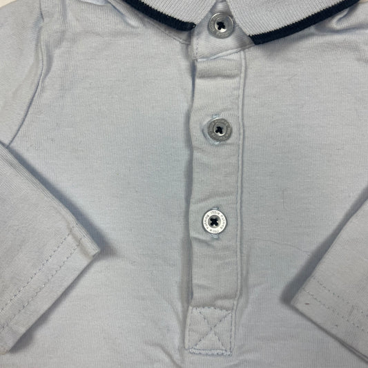 Hellblaues Langarm-Poloshirt mit Knopfleiste und schwarzem Streifen am Kragen. – detail