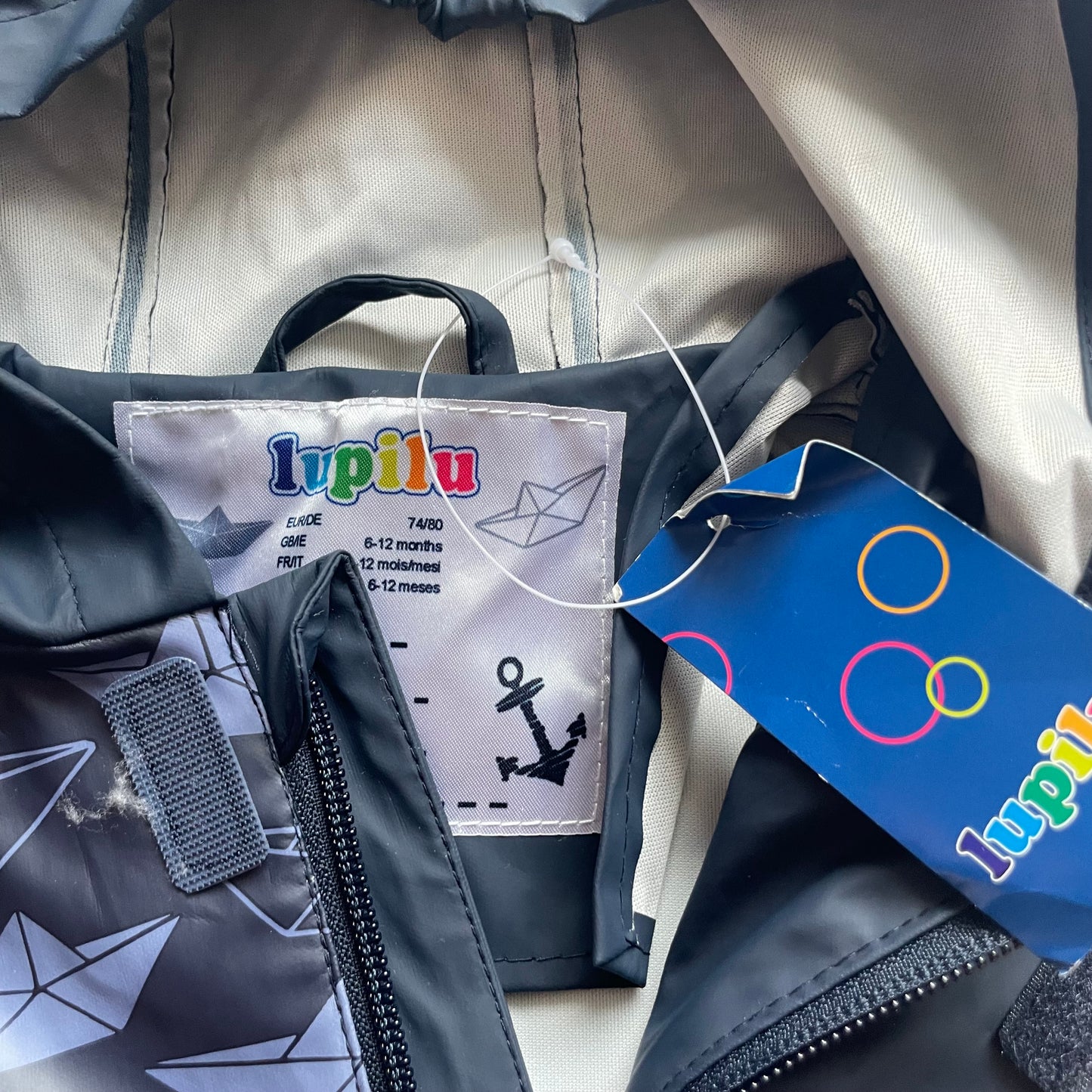 Grauer Regenoverall mit Schiffsprint und Kapuze – tag