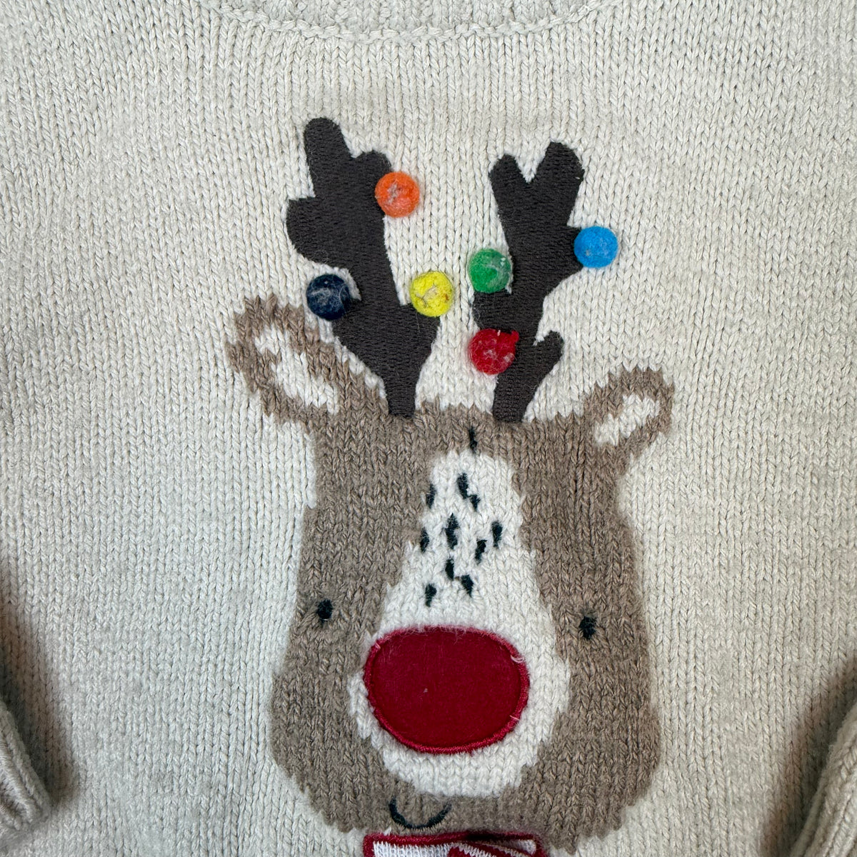 Beiger Kinder-Strickpullover mit Rentier-Motiv und roter Nase – detail