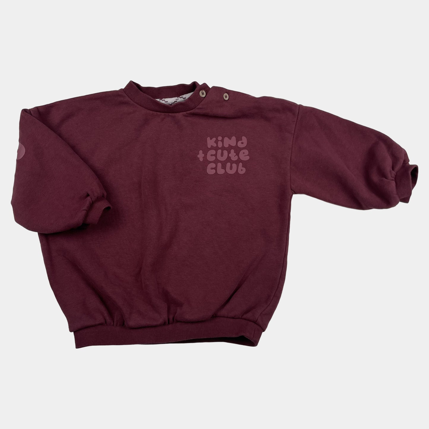 Bordeauxfarbener Pullover mit "Kind Cute Club" Aufdruck und Druckknöpfen an der Schulter. – front