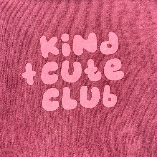 Bordeauxfarbener Pullover mit "Kind Cute Club" Aufdruck und Druckknöpfen an der Schulter. – detail