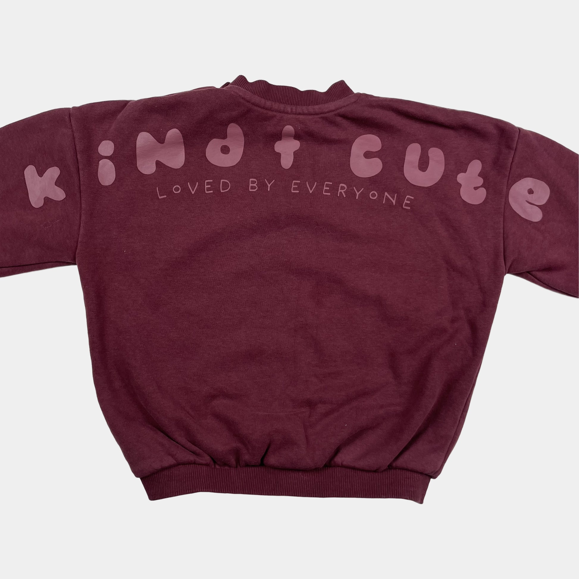 Bordeauxfarbener Pullover mit "Kind Cute Club" Aufdruck und Druckknöpfen an der Schulter. – back