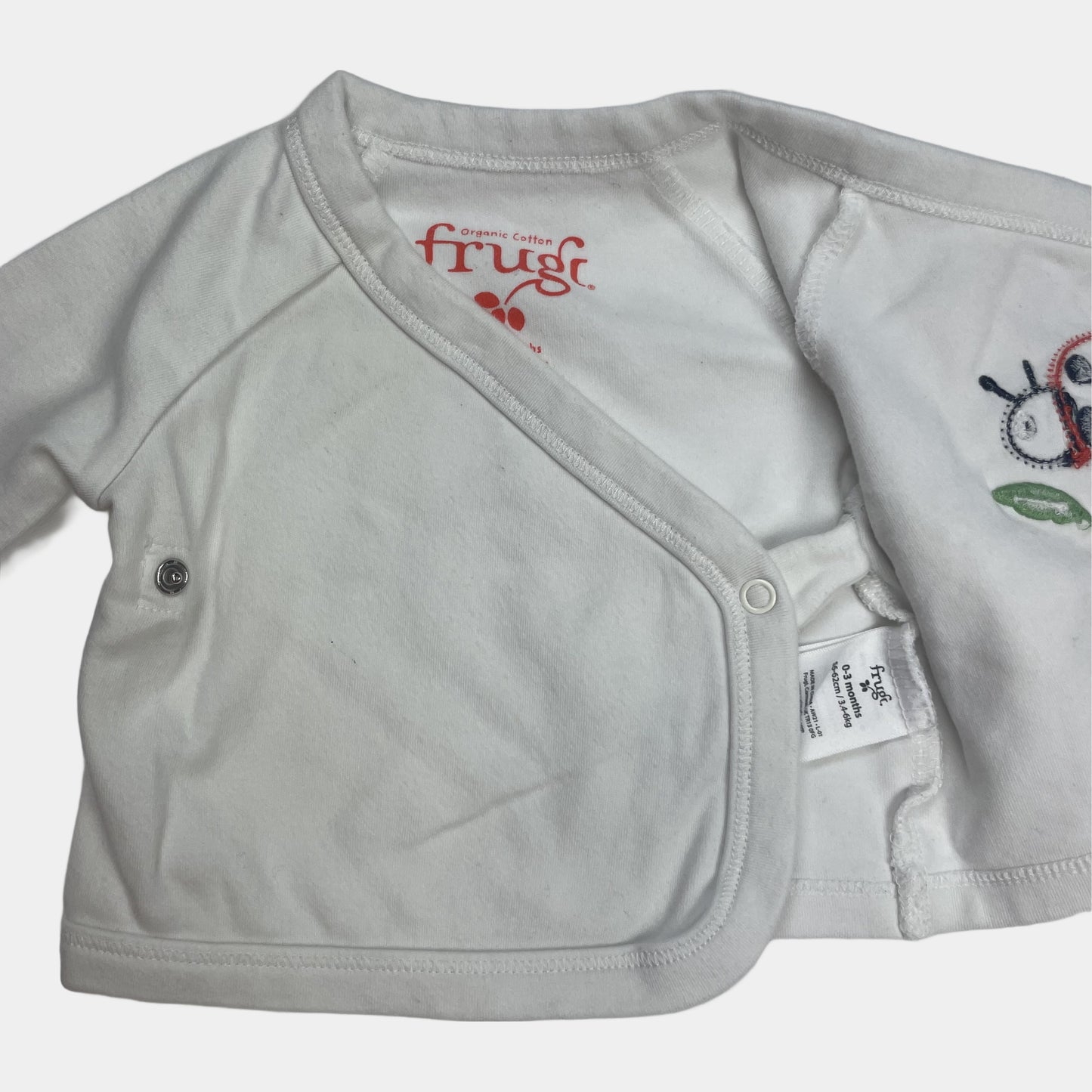 Weißer Baby-Kimono mit Marienkäfer-Applikation auf der Vorderseite – flatlay