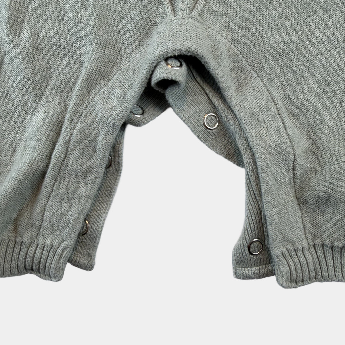 Grauer Strickoverall für Babys mit Zopfmuster und Knöpfen an der Schulter – close‑up