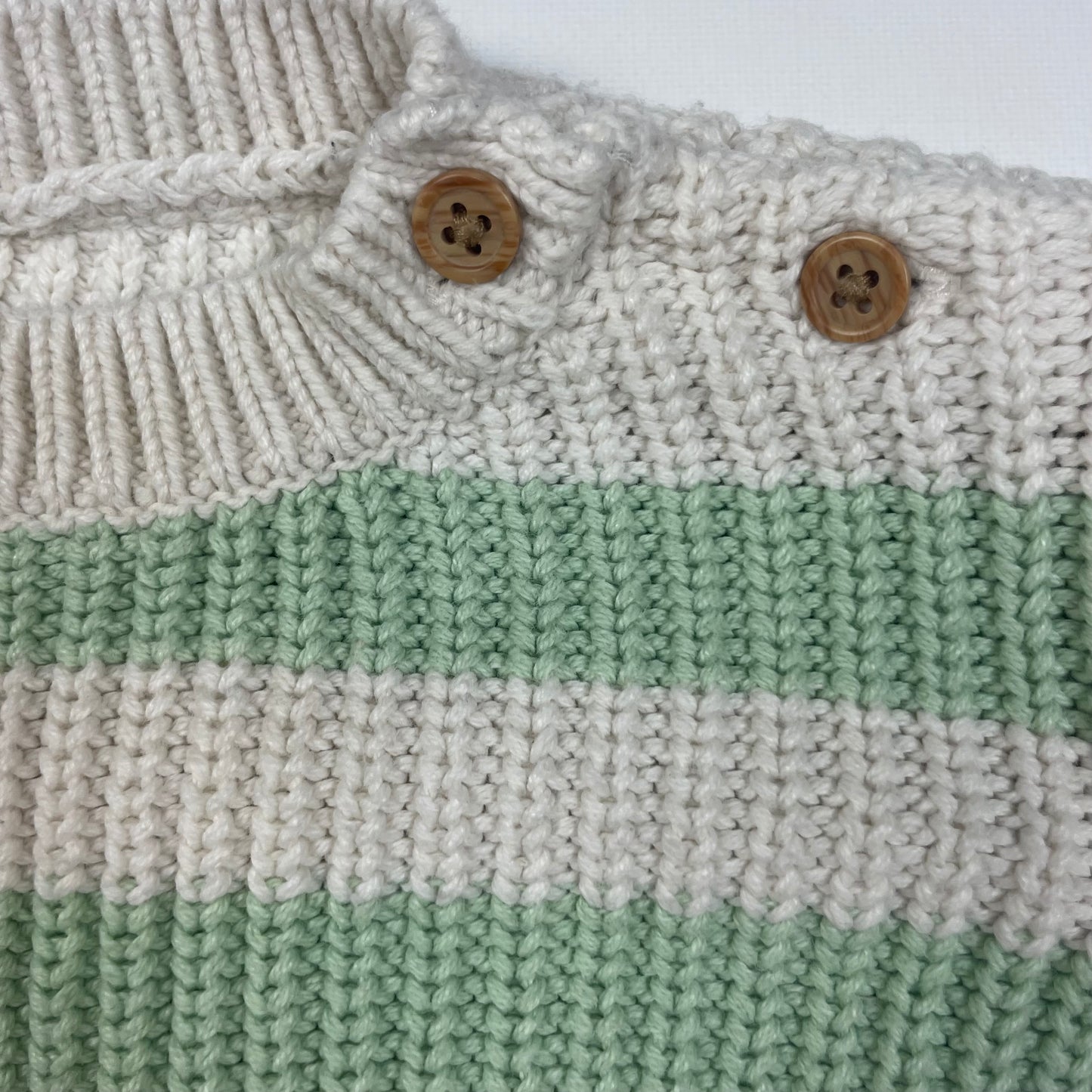 Grüner und weißer Strickpullover mit Streifen und Holzknöpfen für Babys.