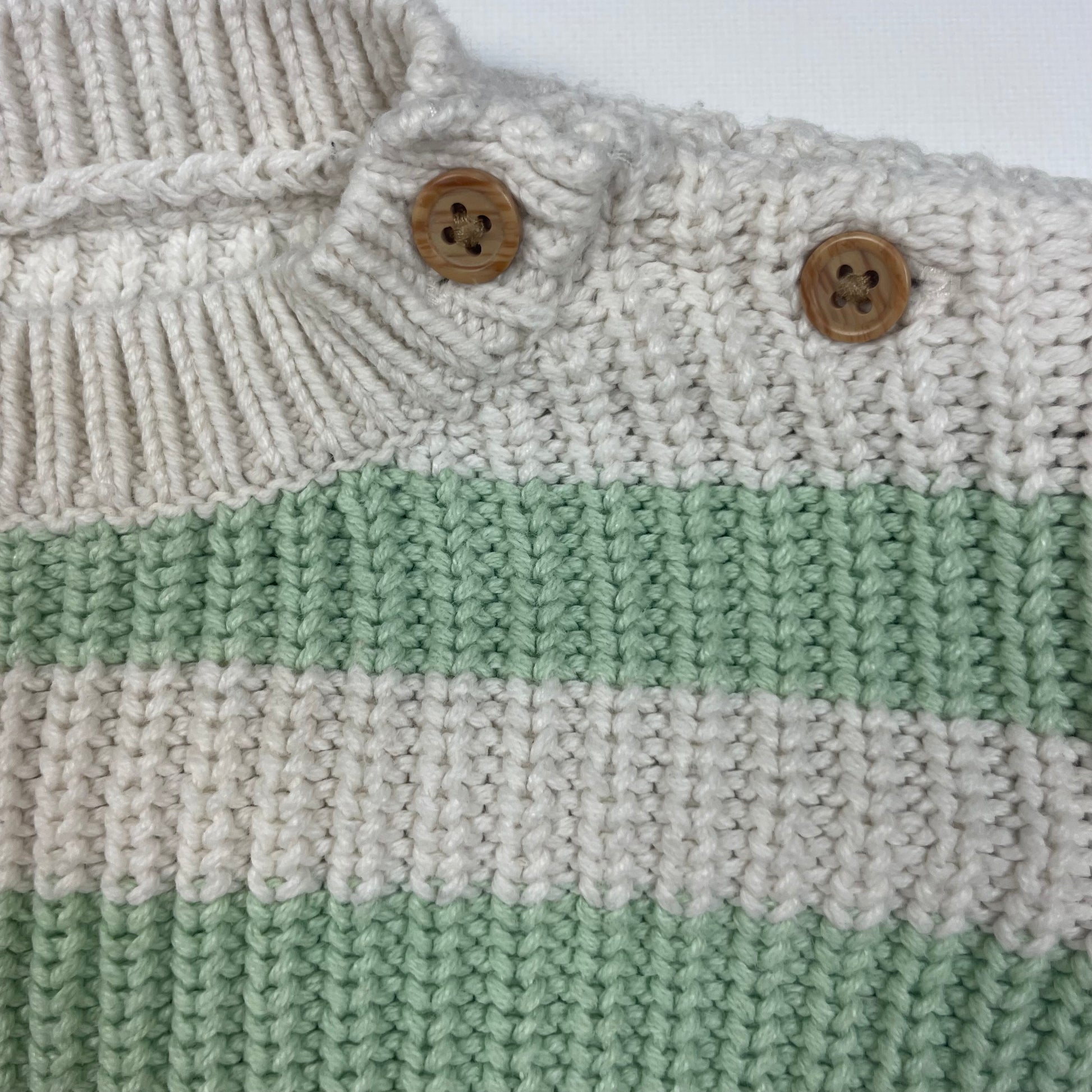 Grüner und weißer Strickpullover mit Streifen und Holzknöpfen für Babys.