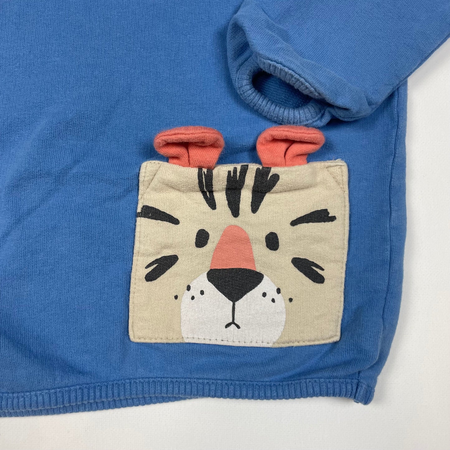 Blauer Pullover mit Tiger-Tasche und Knöpfen seitlich. – detail