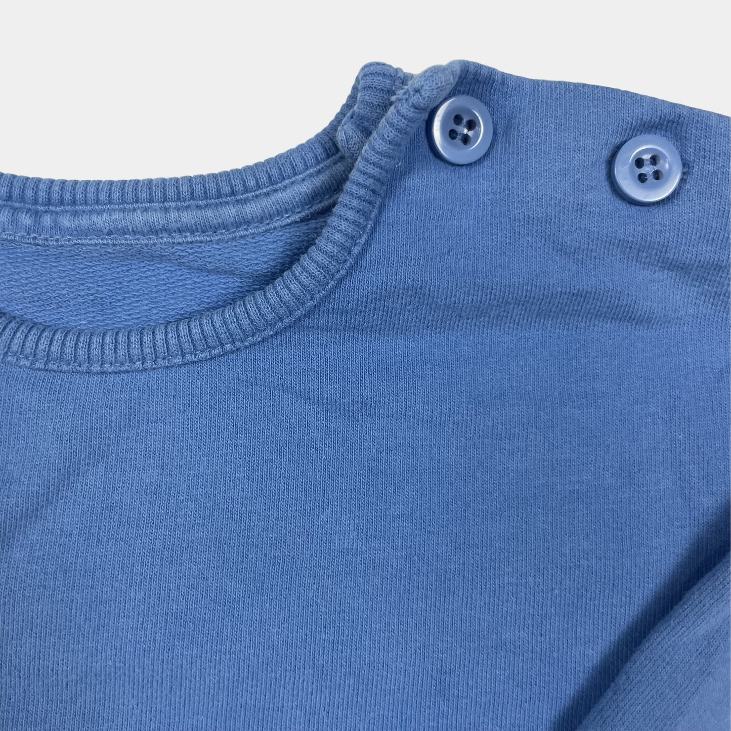 Blauer Pullover mit Tiger-Tasche und Knöpfen seitlich. – close‑up