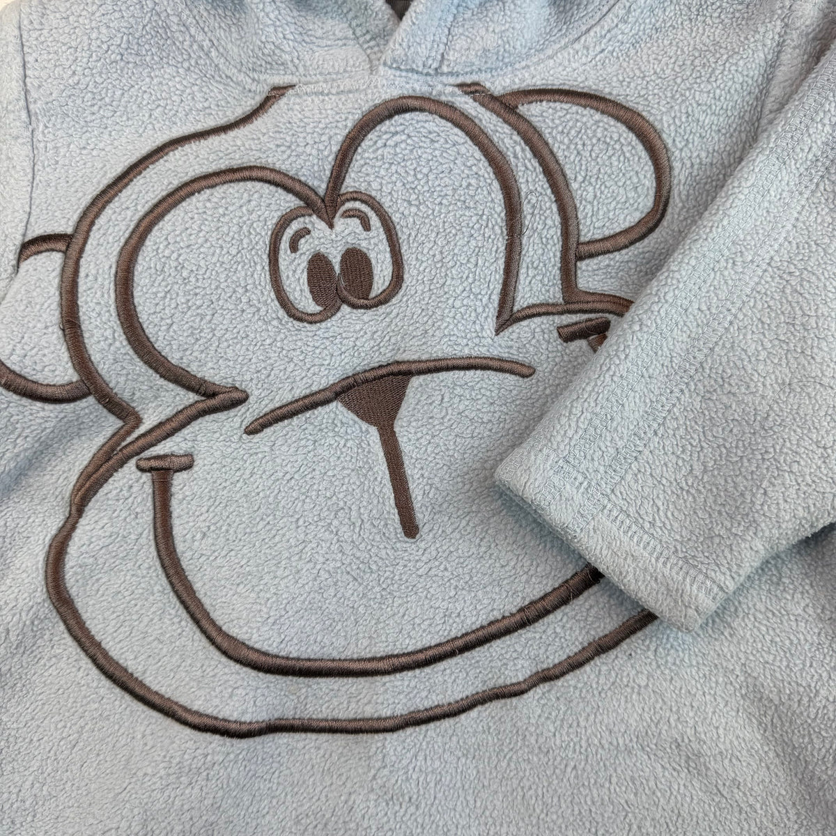 Hellblauer Baby Fleece-Hoodie mit Kapuze und aufgesticktem Tiergesicht – detail