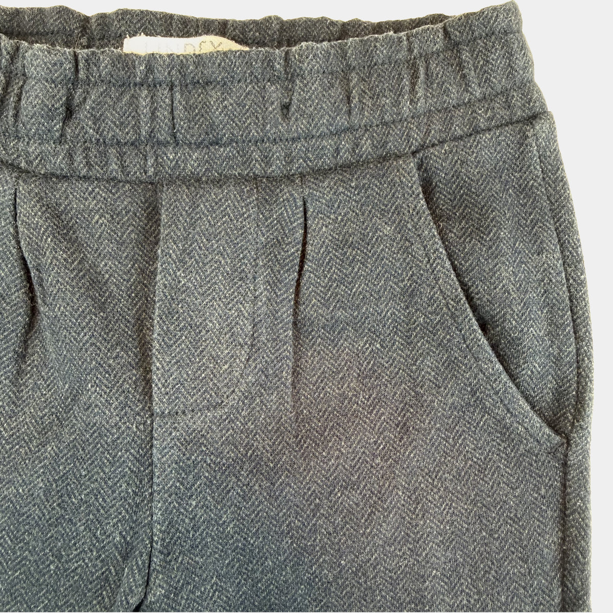Blaue Kinderhose mit elastischem Bund, Zierknöpfen und seitlichen Taschen – close‑up