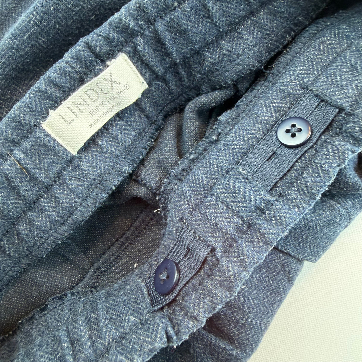 Blaue Kinderhose mit elastischem Bund, Zierknöpfen und seitlichen Taschen – detail
