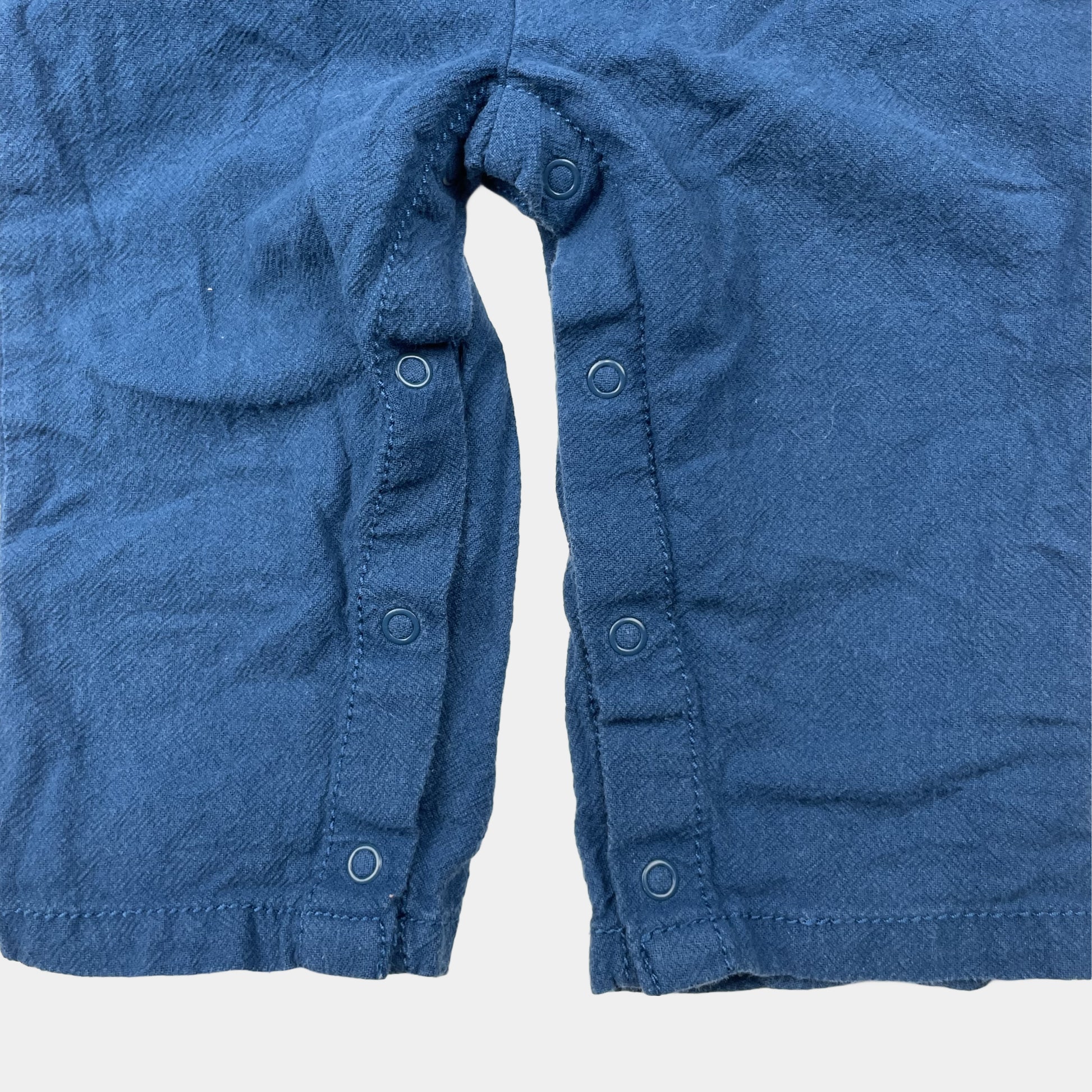 Blauer Overall mit Dinosaurier-Stickerei und Knöpfen – close‑up