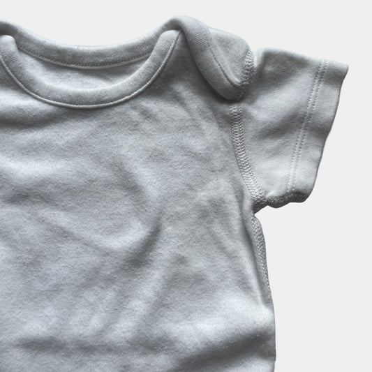 Weißer Babybody aus Baumwolle mit kurzen Ärmeln und Druckknöpfen im Schritt. – detail