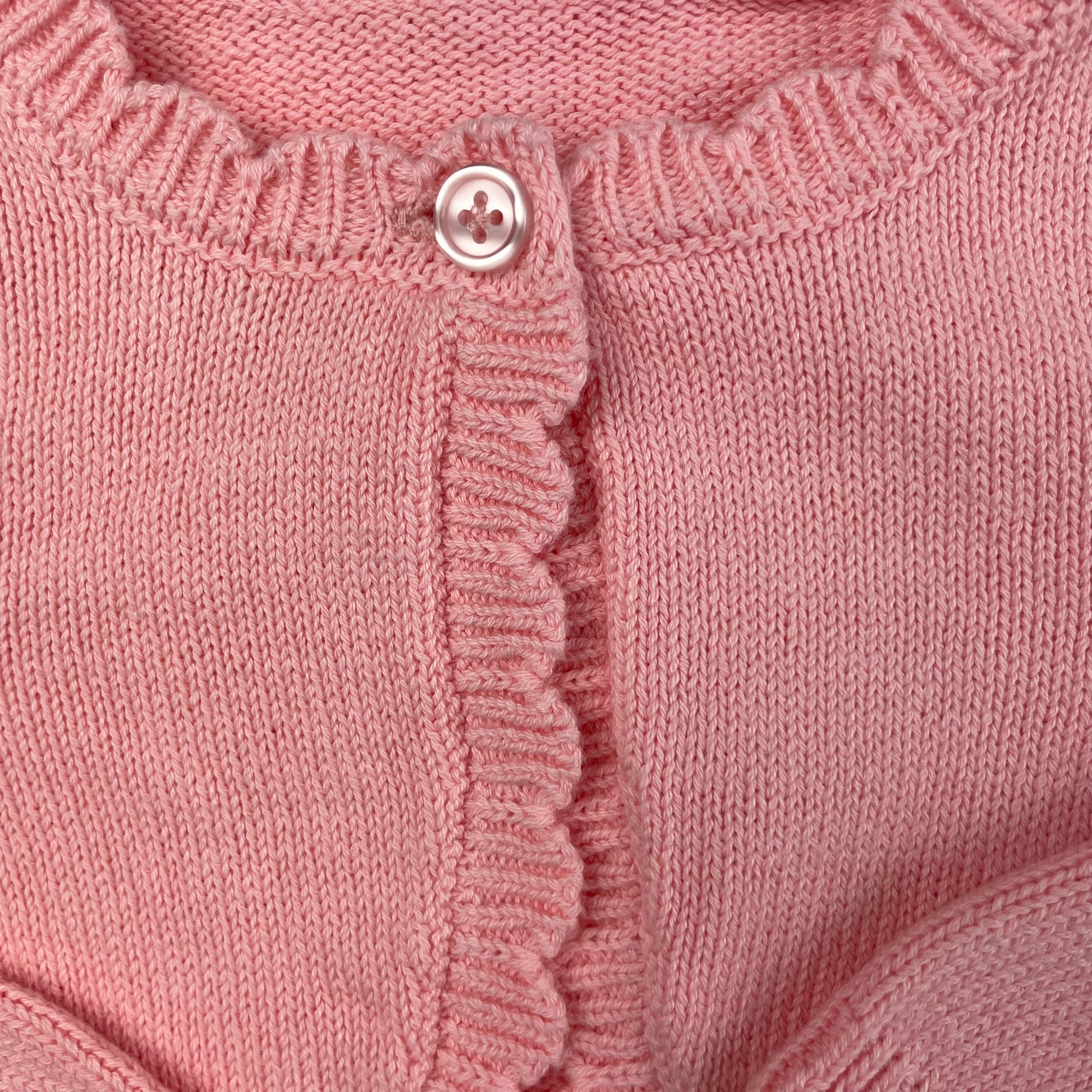 Rosa Strickjacke für Babys mit Rüschen und Knopfverschluss – close‑up